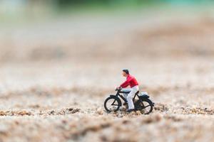 Viajero en miniatura en bicicleta, explorando el concepto del mundo. foto