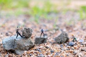 Miniature workers on a rock, teamwork concept photo
