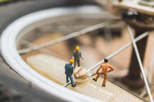 Miniature mechanics repairing a bicycle, workshop concept photo