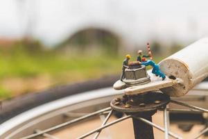 Mecánica en miniatura reparando una bicicleta, concepto de taller foto