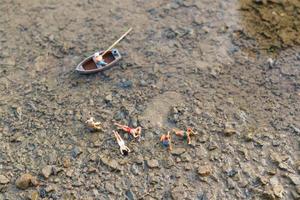 Miniature people wearing swimsuits relaxing on a beach, summer concept photo