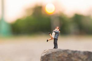 Miniature couple standing on a rock cliff photo