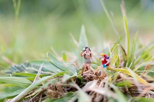 Miniature traveler with backpacks walking in the field, travel and adventure concept photo