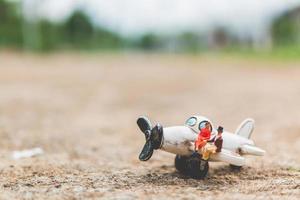 Pareja en miniatura sentada en un avión, explorando el concepto del mundo foto