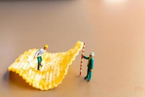 Trabajadores en miniatura que trabajan con papas fritas. foto