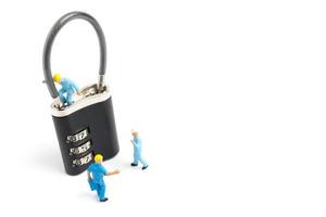 Miniature workers unlocking the password on a lock, teamwork concept photo