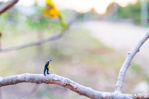 Trabajador en miniatura cortando ramas de árboles, concepto de deforestación foto