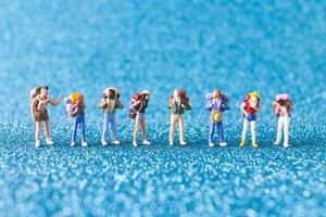 Miniature backpackers, tourist people on a blue glitter background photo