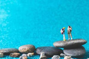 Mochileros en miniatura, gente turística sobre un fondo azul brillante