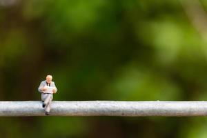 Miniature businesspeople sitting on a wire with a green background, business team concept photo