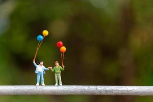 Familia en miniatura sosteniendo globos de colores, concepto de familia feliz