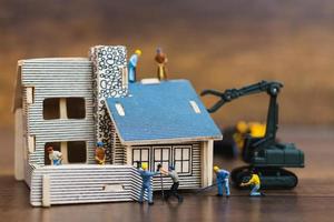 Trabajadores en miniatura construyendo un hogar, concepto de renovación del hogar foto