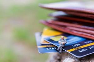 Miniature businesspeople sitting on a credit card, business and finance concepts photo