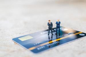Empresarios en miniatura de pie sobre una tarjeta de crédito, conceptos comerciales y financieros