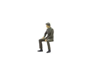 Miniature businessman sitting isolated on a white background photo