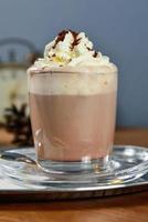 Glass cup of cocoa with whipped cream on wooden table