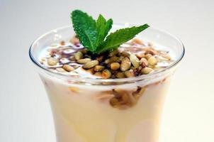 Yogurt with honey and pine nuts in clear glass on white background photo