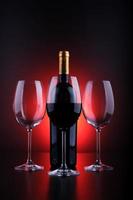 Wine bottles and full glass with red and black background