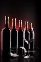 Botellas de vino y vasos con fondo negro y rojo. foto