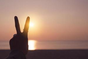 Peace out hand sign in front of a sunset photo