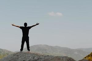 Man with raised hands with blue sky and mountain in summer background photo