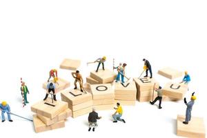 Miniature workers building the word Love on wooden blocks with a white background, Valentine's Day concept photo