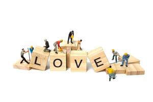 Miniature workers building the word Love on wooden blocks with a white background, Valentine's Day concept photo