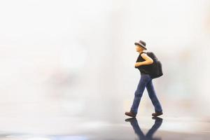 Miniature traveler with a backpack walking on empty space, travel concept photo