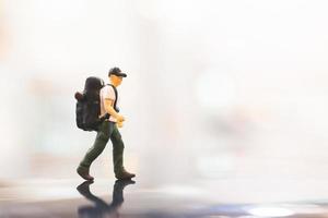 Viajero en miniatura con una mochila caminando sobre un espacio vacío, concepto de viaje foto