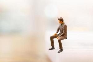 Miniature businessman sitting on empty space photo