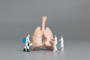 Miniature doctors and nurses observing and discussing the human lung, virus and bacteria-infected concept photo