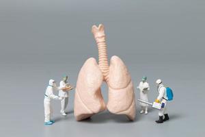 Miniature doctors and nurses observing and discussing the human lung, virus and bacteria-infected concept