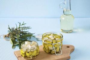 Marinated feta in a glass jar and spices against a blue background photo