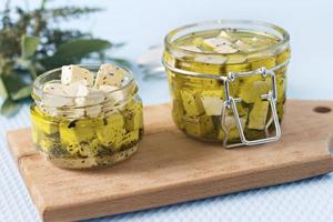 Marinated feta in a glass jar and spices against a blue background photo
