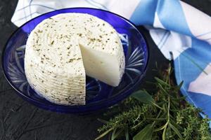 Queso blanco en un plato sobre un fondo negro y servilleta foto