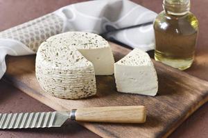 White cheese on a wooden board with olive oil on a brown background photo