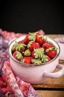 Strawberries in a bowl on a wooden table photo