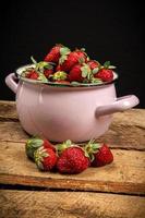 Strawberries in a bowl on a wooden table photo