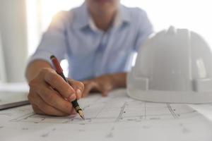 Man working on a blueprint next to hard hat