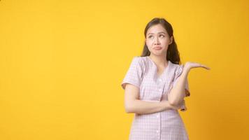Asian woman with arms crossed and one palm up on yellow background photo