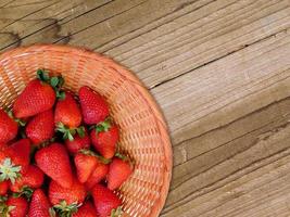 Strawberries in a wicker bowl on a wood table background