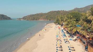 Luft 4k Drohnenaufnahmen von Besuchern, die einen tropischen Strand von Palolem, Indien genießen.
