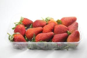 Fresas en un recipiente de plástico sobre un fondo blanco. foto