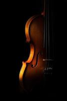 Violin detail on a black background between light or shadows photo