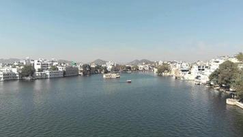 Overview of Pichola Lake to the Mohan Mandir Temple in Udaipur, in Rajasthan, India - Aerial Low-angle Fly-over shot video