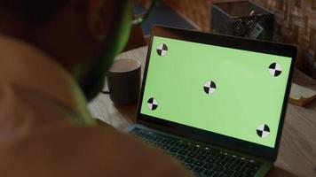Cerca de la pantalla verde en el portátil, las manos del hombre negro sosteniendo la pantalla video