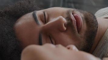 Close up of young Middle Eastern man, smiling, talking, lying on his back on floor with young mixed race woman video