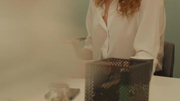 White young woman and black mature woman sitting at table in office, white woman points, black woman watches video