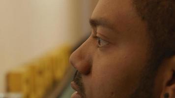 Extreme close up of black man looking straight ahead, hand holds marker close to his face video