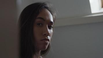 Close up, profile of young mixed race woman, looking straight ahead, turns face to camera, eyes blinking
